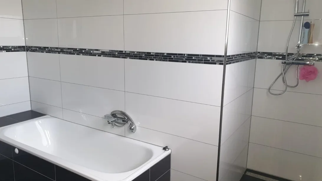 Fertig gefliestes Bad mit Mosaikbordüre über der Badewanne