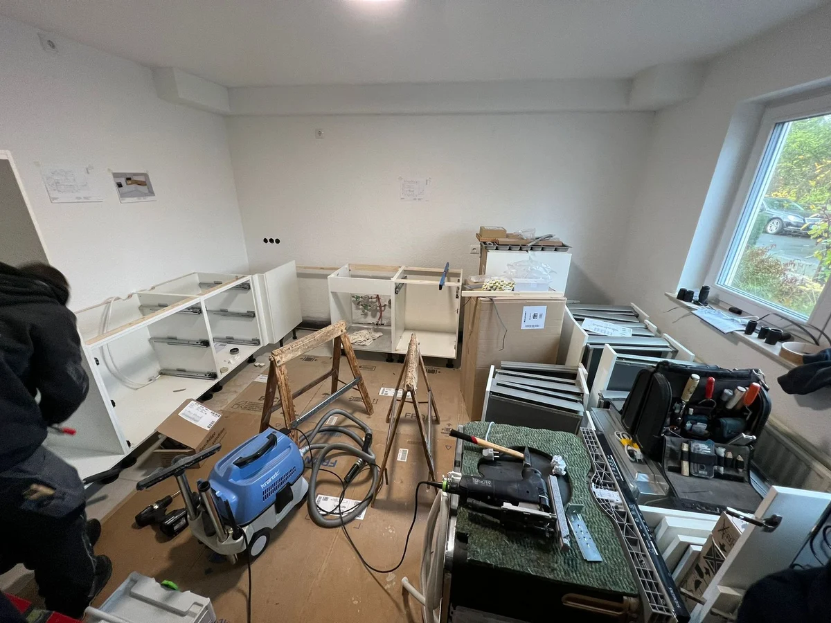 Die Küchenkorpusse stehen aufgebaut, Werkzeug und Sauger im Raum
